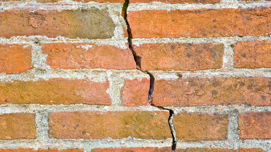 Photo of brick wall with large structural crack running through it.