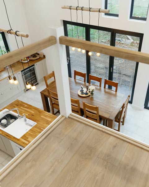 Featured image of barn conversion interior looking down from the mezzanine across an open plan kitchen diner.