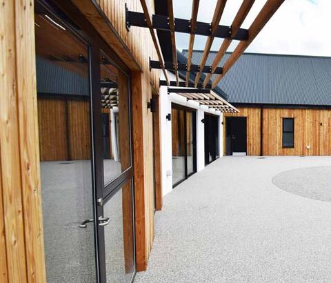 Featured image of the modern new build bungalow with full height windows overlooking accessible garden.